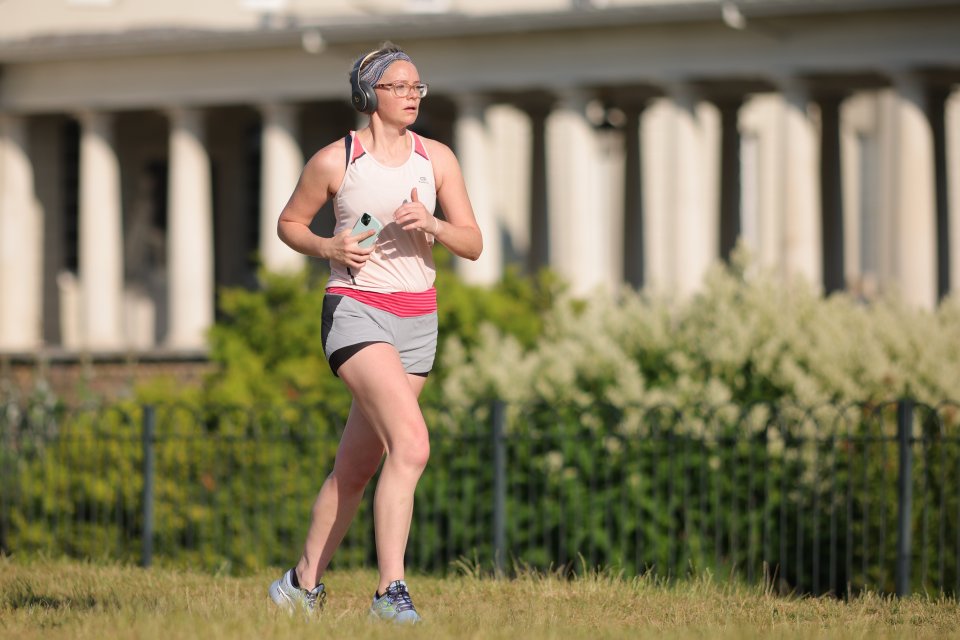 A runner enjoys the early morning sun in London's Greenwich Park this morning