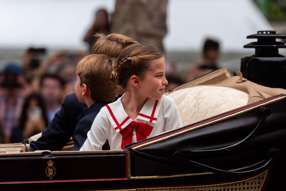 Cheeky Princess Charlotte sat next to her brothers wearing a cute white dress with a red trim and neck scarf