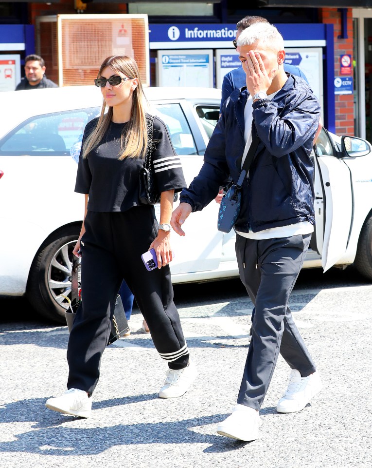 Lisandro Martinez covers his face as he walks with girlfriend Muri Lopez