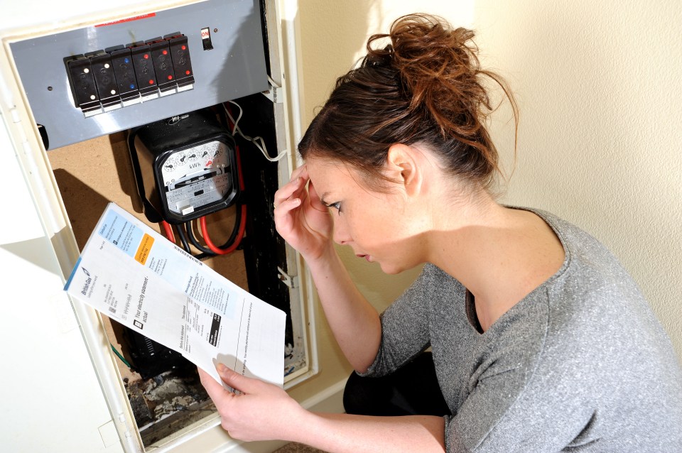 D61YF1 Young woman 20s attempting to read and understand her electricity meter reading and energy bill. Image shot 04/2013. Exact date unknown.