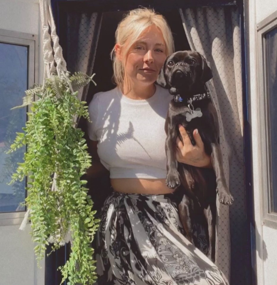 Woman holding a small black dog in a doorway.