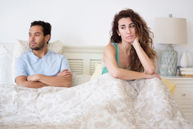 a man and a woman are sitting on a bed with their arms crossed