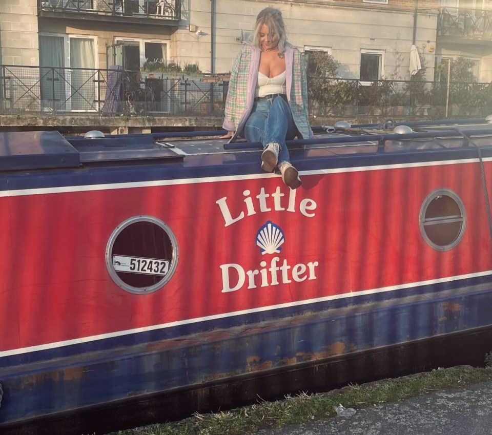 Woman sitting on the roof of a barge named Little Drifter.