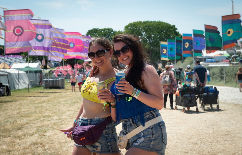 Festival-goers beam as they enjoy a drink in the sunshine after arriving at the Isle Of Wight Festival