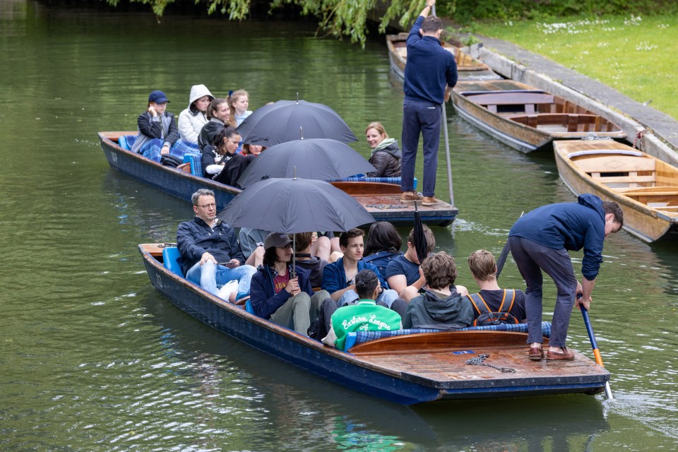 People shelter themselves from the rain on Tuesday as they travel on the River Cam in Cambridge