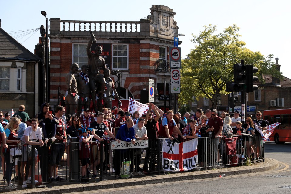 Fans line the street at the parade in front of the statue of Bobby Moore