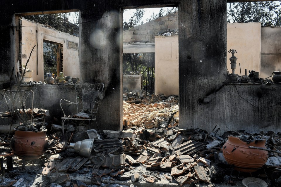 A photograph shows a burned house after a wildfire hit near Agioi Theodori