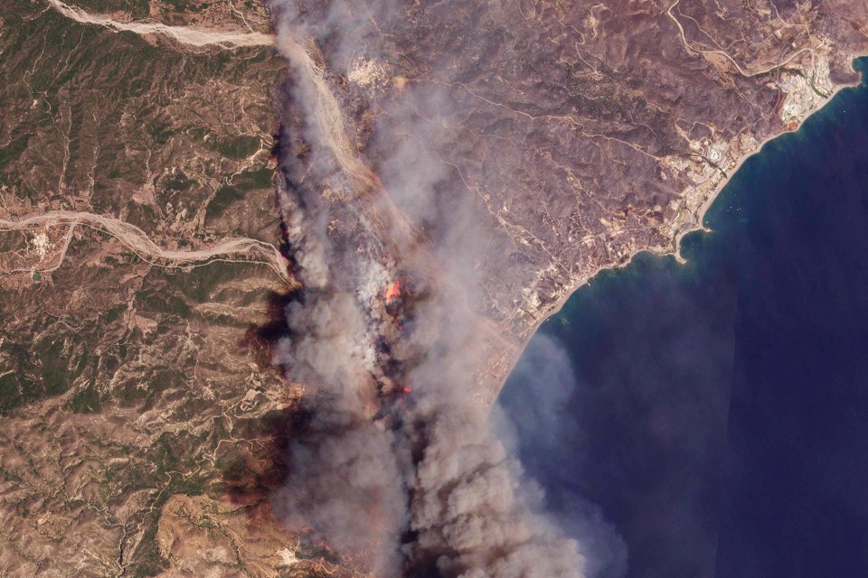 A satellite image from Planet Labs PBC shows the fires burning on the Greek resort island of Rhodes