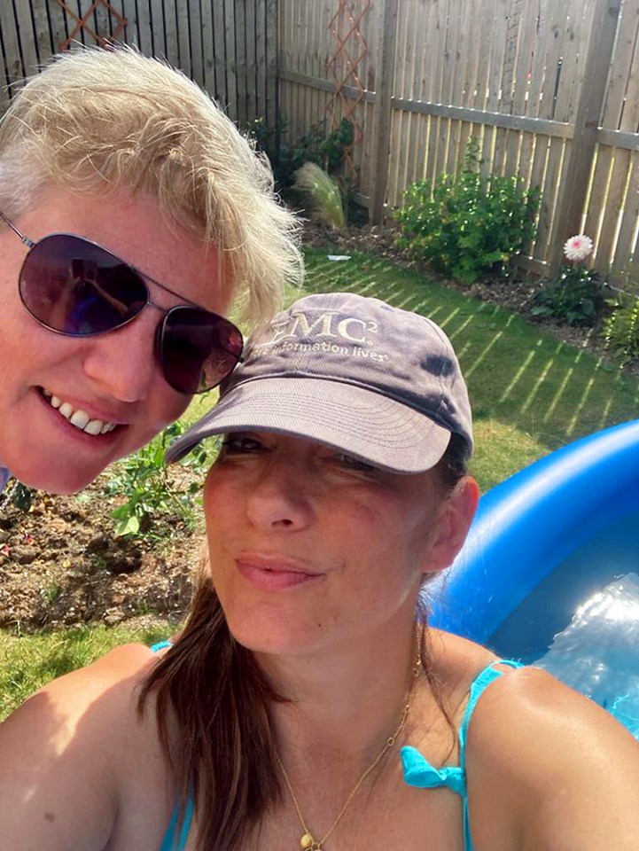 Selfie of two women in a garden, one wearing sunglasses and the other a baseball cap.