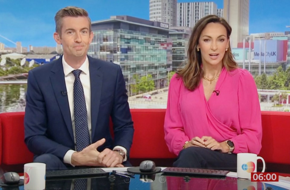 a man and a woman are sitting in front of a bbc building