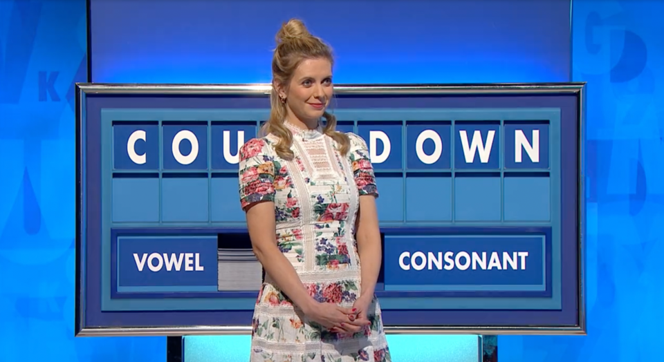 Countdown's Rachel Riley standing in a figure hugging floral dress with the countdown board behind her