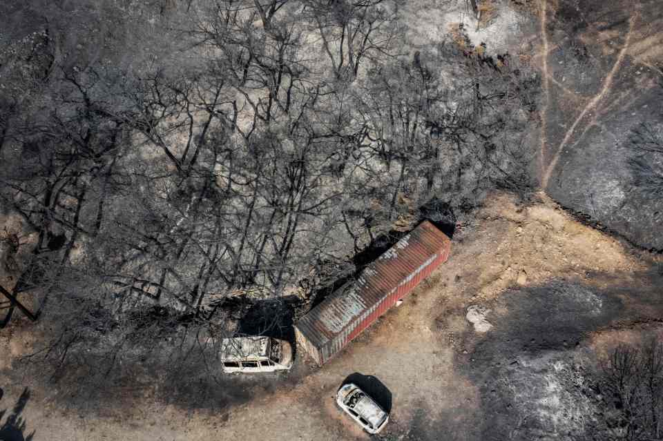 An aerial view shows burnt vehicles and trees after a fire near Vati