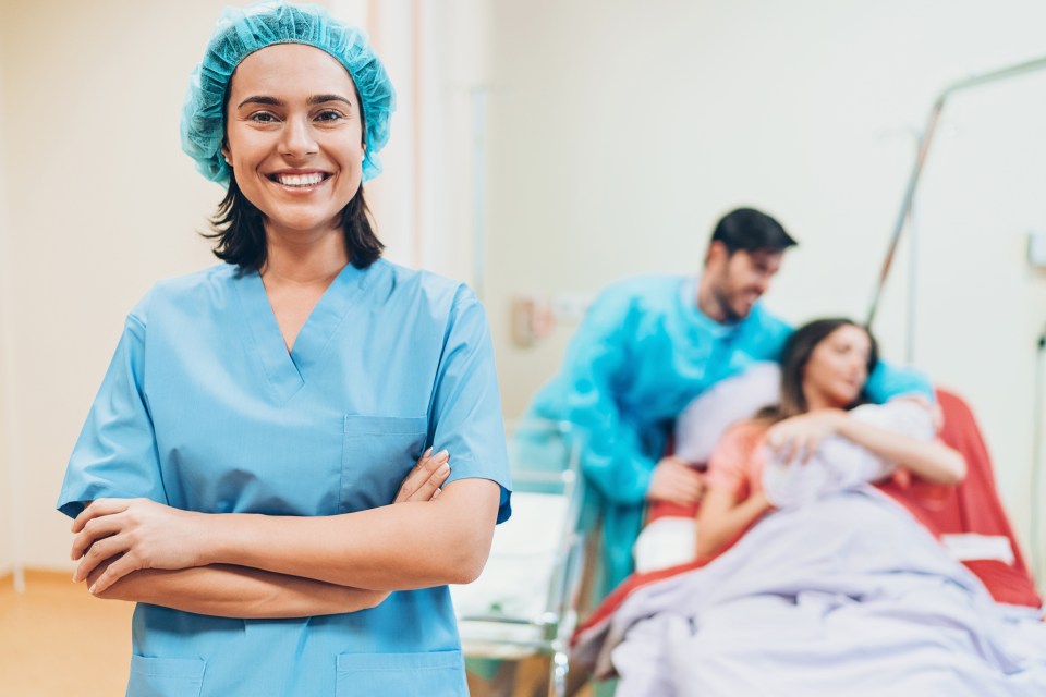 Happy midwife in front of a young family with a newborn baby