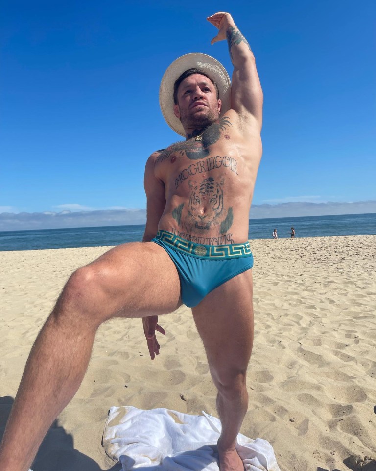 Conor McGegor stretching off in his budgie smugglers during a family beach day