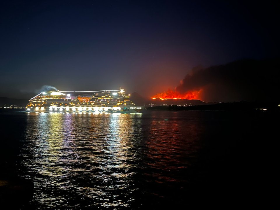 A cruise ship sails past as raging wildfires burn on the island of Corfu