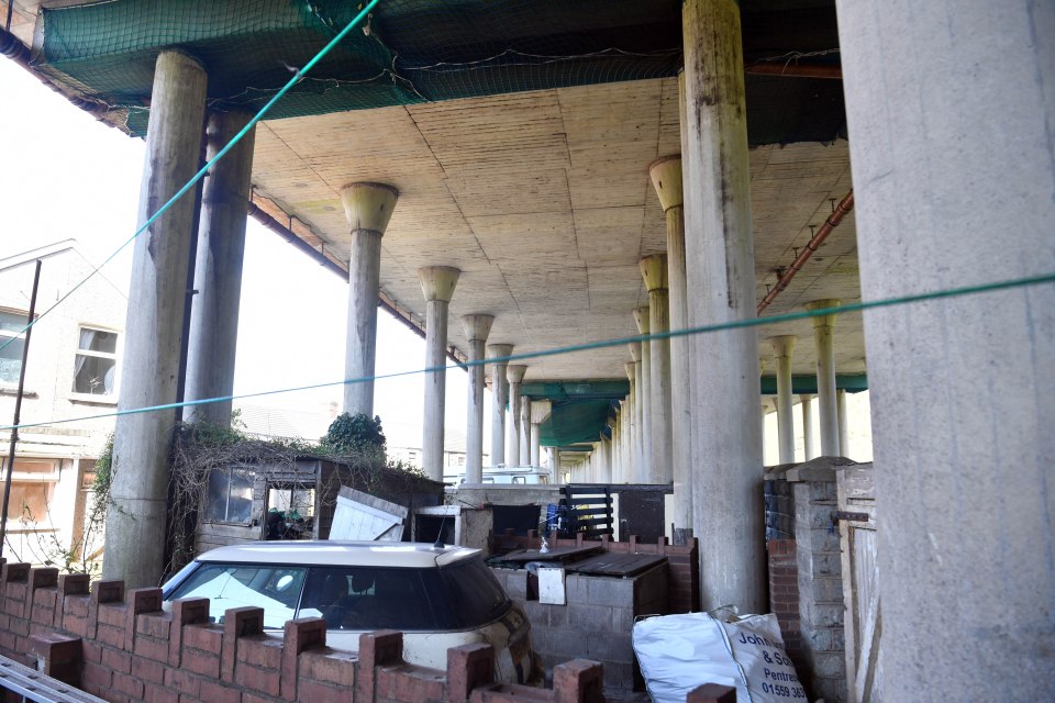 Massive pillars supporting the motorway are planted in locals' gardens