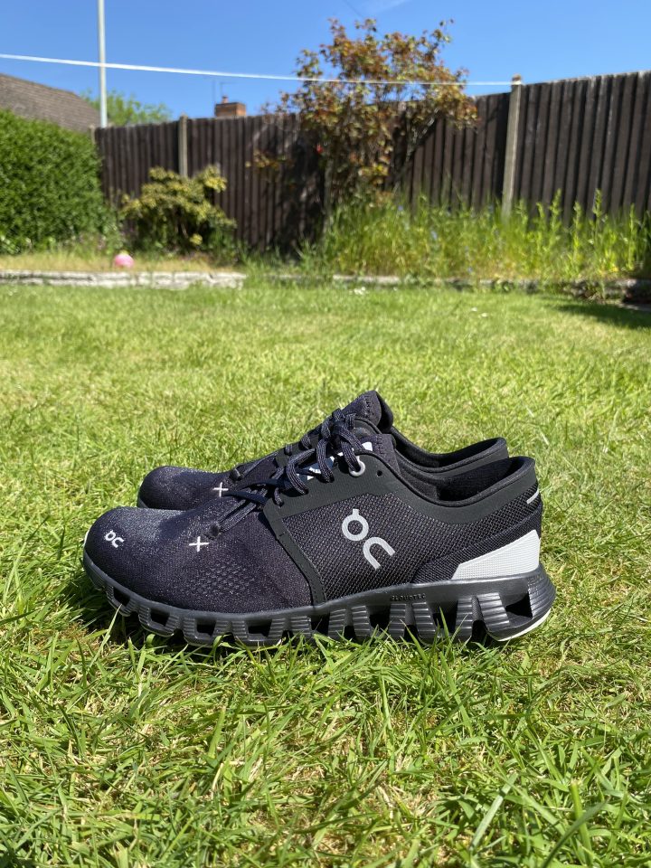 Pair of black On Cloud running shoes on grass.