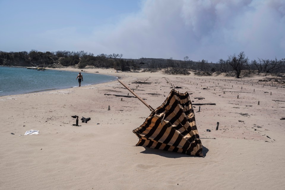 Burnt sunbeds and umbrellas strewn across a beach on the island of Rhodes