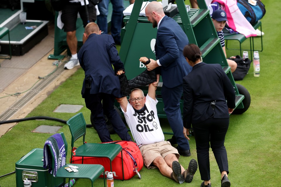 An eco-loon is dragged away by security at Wimbledon