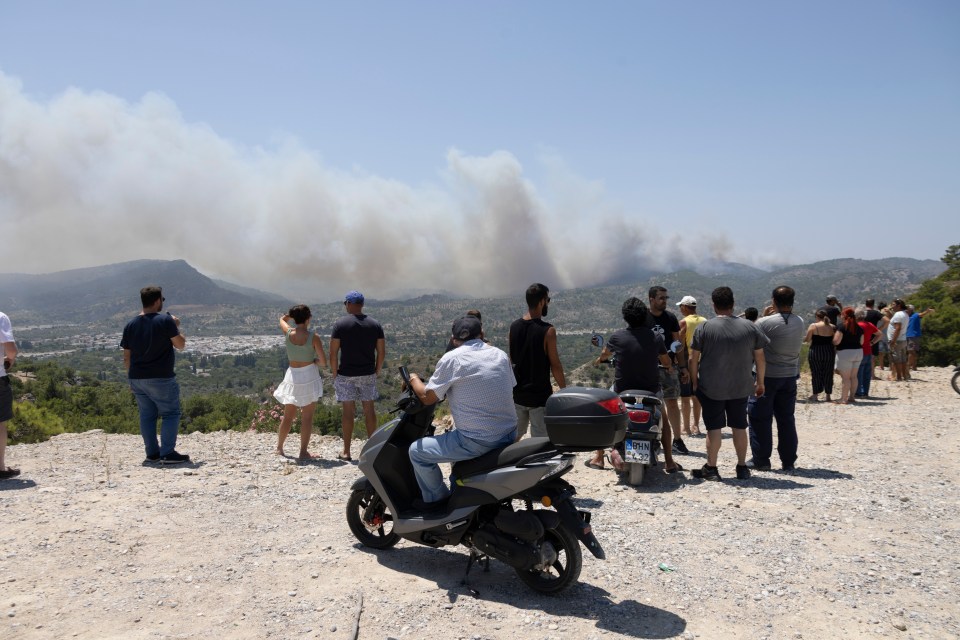 Locals and tourists watch as fires continue to spread across the island