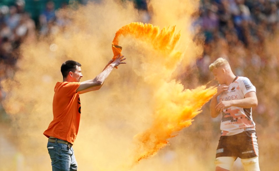 Activists have run onto the field of play to hurl orange dust in an attempt to spread their message of climate catastrophe