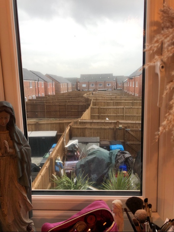 The photo appears to show rear gardens of new build homes with fence after fence