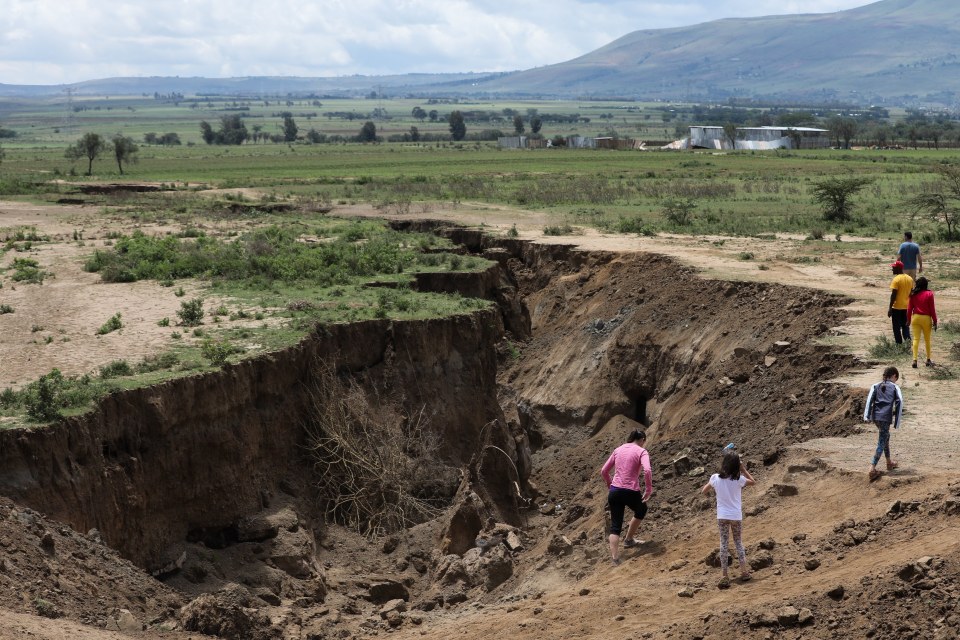 epa06650854 People gaze and take pictures of a huge crack that has sliced through the ground around the Rift Valley area close to Mai Mahiu town, some 50 km southwest of Nairobi, Kenya, 06 April 2018. The sudden appearance of the crack have forced residents to flee their homes and farms. The fissures may be caused by seismic activity and erosion caused by heavy rains. EPA/DANIEL IRUNGU