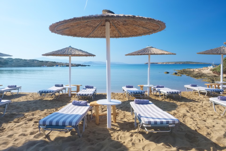 P4FF6B Umbrellas with sunbeds on beautiful sandy Santa Maria beach with turquoise sea water, Paros island, Greece