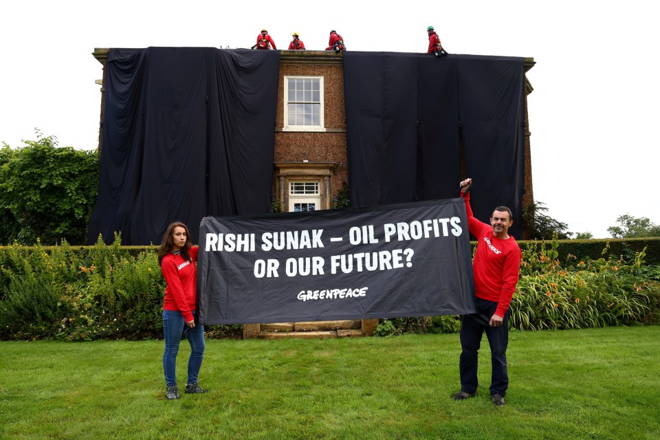 Greenpeace activists hold a banner while others cover British Prime Minister Rishi Sunak's £2m manor house in oil-black fabric in protest of his backing for a major expansion of North Sea oil and gas drilling amidst a summer of escalating climate impacts, in Yorkshire, Britain August 3, 2023. Greenpeace/Handout via REUTERS THIS IMAGE HAS BEEN SUPPLIED BY A THIRD PARTY. NO RESALES. NO ARCHIVES. MANDATORY CREDIT. NO USE AFTER AUGUST 17, 2023.