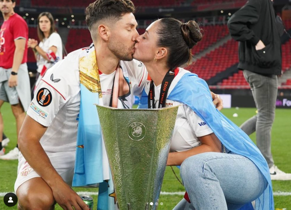 Karina and Montiel share a kiss in front of the Europa League trophy