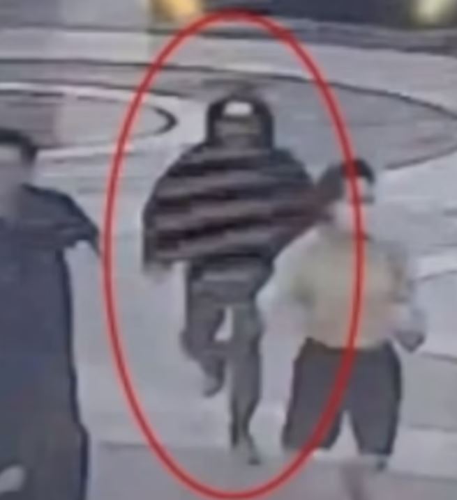 The suspect dressed in dark clothes can be seen brandishing a knife