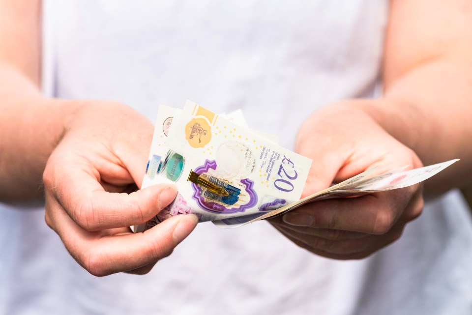 Close-up as a woman counts out modern British banknotes.