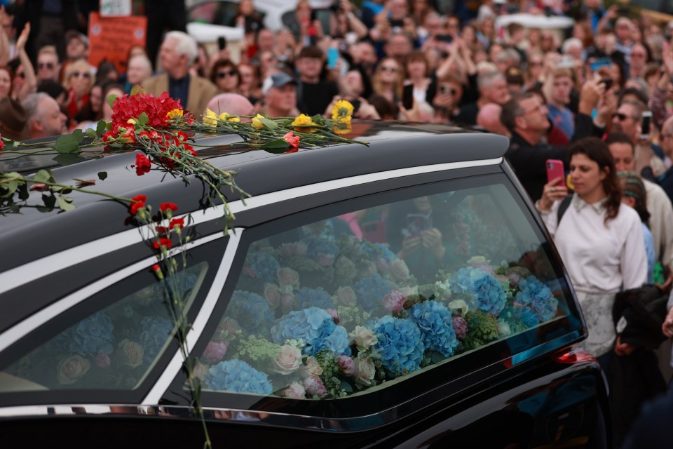 Fans of the singer threw flowers on the hearse carrying her coffin