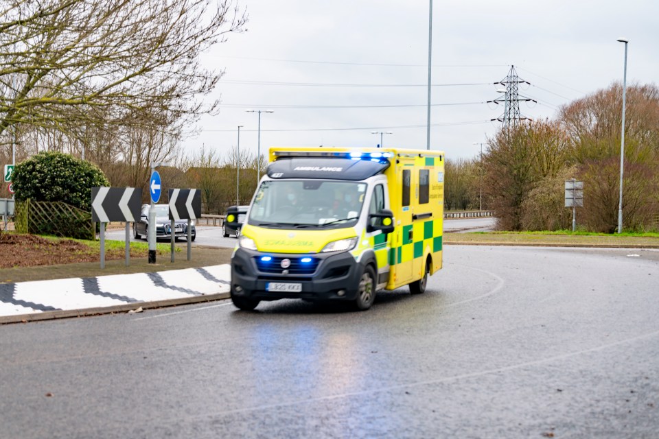 Hinchingbrooke Hospital Entrance roundabout. There is an ambulance with blue lights going to an emergency around a roundabout outside the hospital. It is part of the North West Anglia Foundation Trust.  Huntingdon, Cambridgeshire, England, UK.