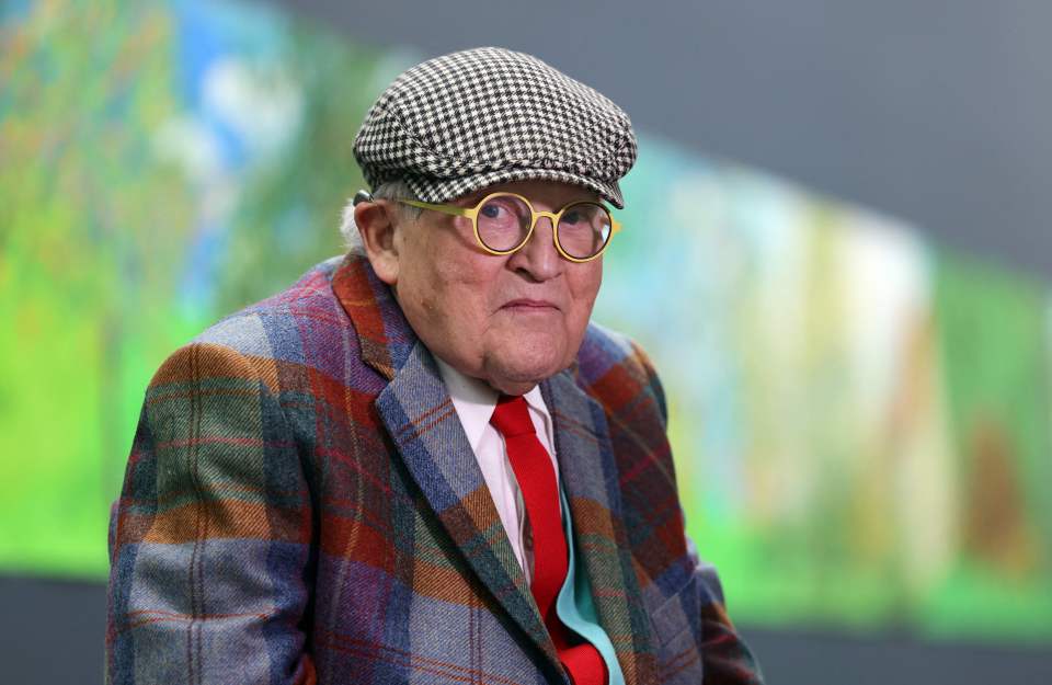 The British artist painted Harry wearing jeans and a striped orange and red cardigan, relaxing in a cane chair