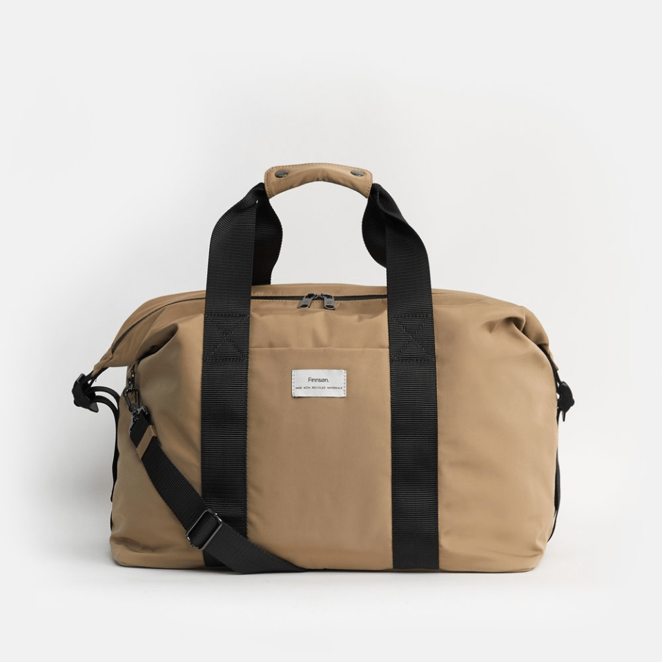 Tan duffel bag with black straps and shoulder strap.