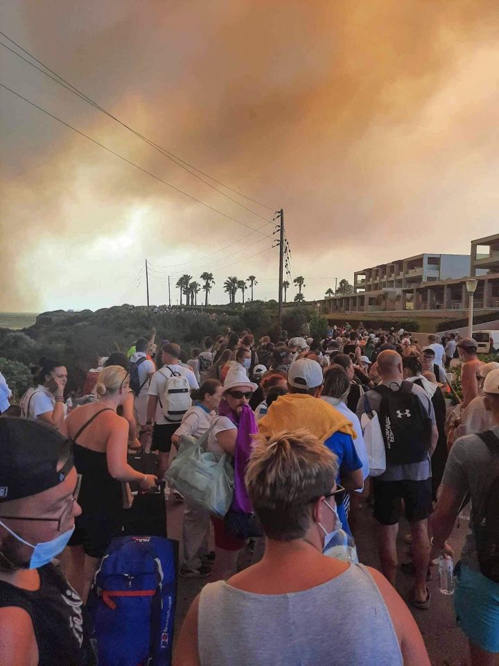 Tourists are evacuated from hotels during a wildfire on the Greek island of Rhodes on July 22, 2023. Three coastguard boats were leading more than 20 vessels in an emergency evacuation effort to rescue people from the Greek island, where fire has been raging out of control for five days. (Photo by STRINGER / Eurokinissi / AFP) (Photo by STRINGER/Eurokinissi/AFP via Getty Images)