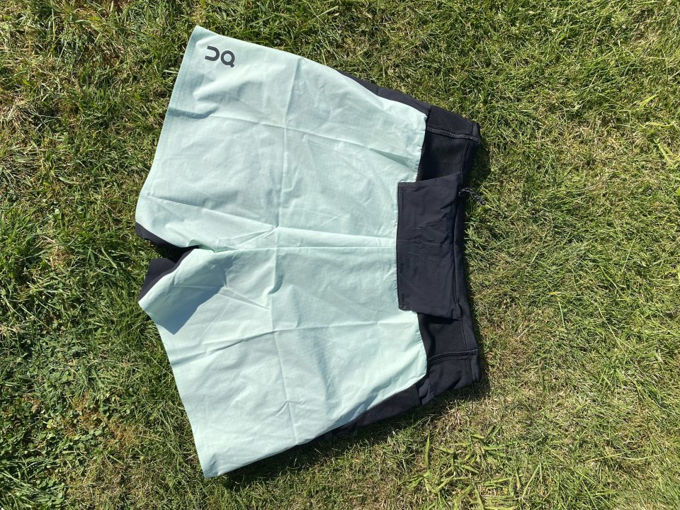 Mint green and black running shorts on the grass.