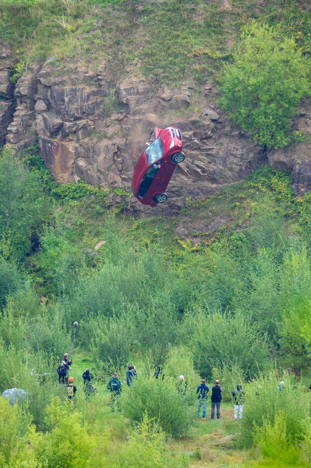 The car goes off the cliff with a red-haired mannequin inside