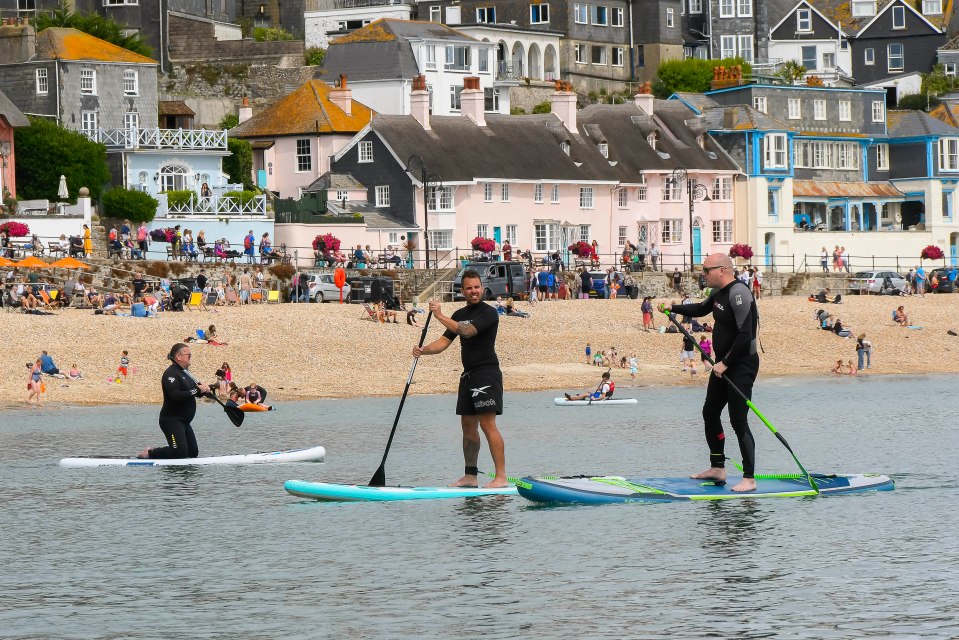 Paddle boarders having fun on the calm sea in Lyme Regis on Sunday