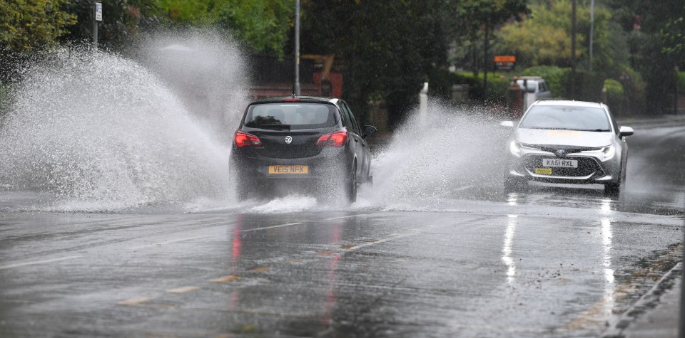 Cars drive through a flooded road in Manchester on Sunday