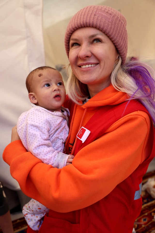 Red Crescent volunteer Anastasia Ozdemir holds one-year-old Yusuf Ali