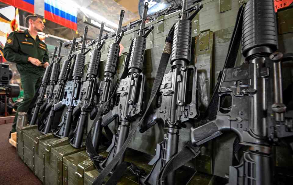 A Russian Army Major stands next to a row of US assault rifles