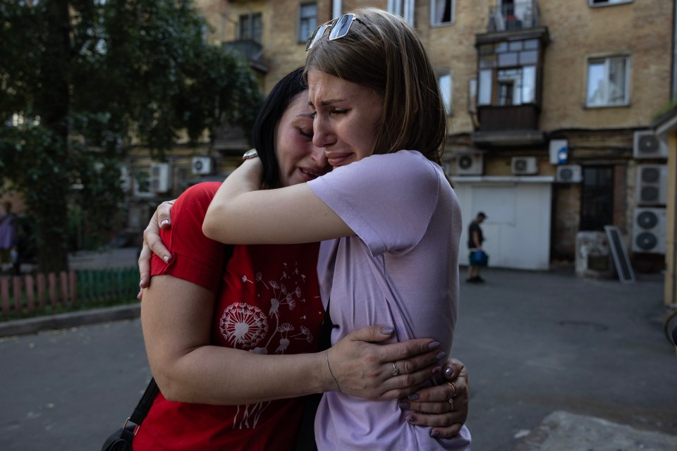 Workers from the Vertel cafe hug before cleaning up after a missile attack in the center of Chernihiv