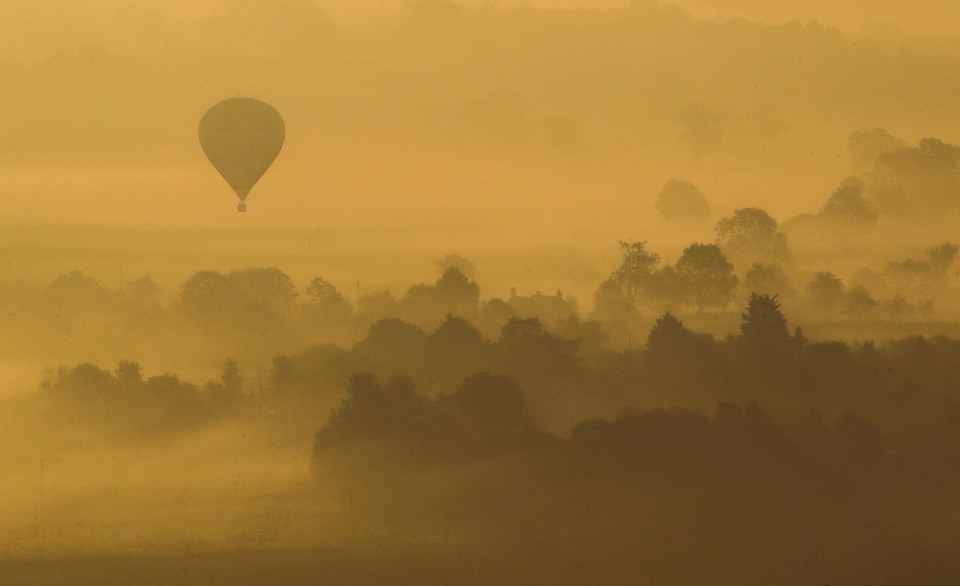 A hot air balloon flew over a misty West Pennard in Somerset on Friday