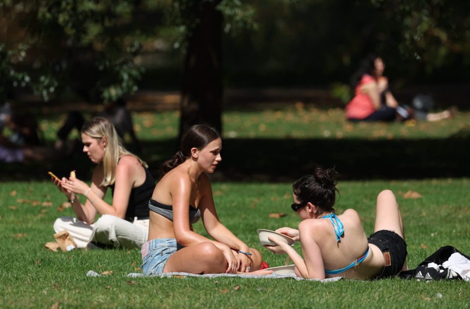 People topping up their tan at St James' Park in London this afternoon