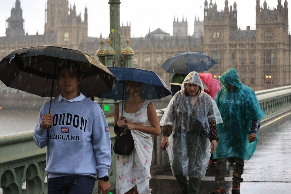 People crossing Westminster Bridge, central London, get caught in a downpour yesterday