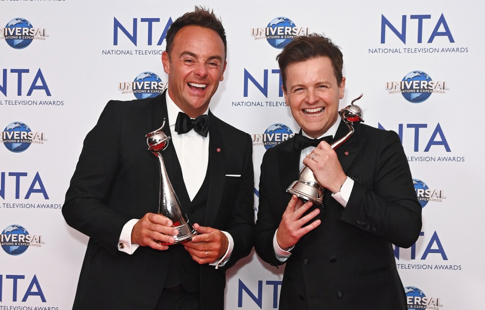 two men holding trophies in front of a wall that says nta