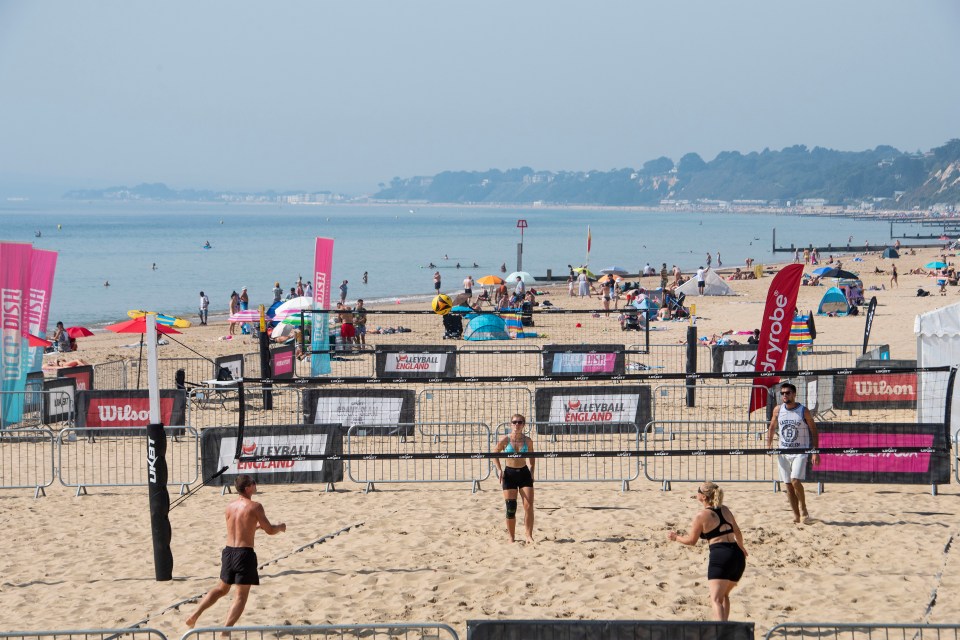 Beach goers playing volleyball on a morning of bright sunshine in Bournemouth