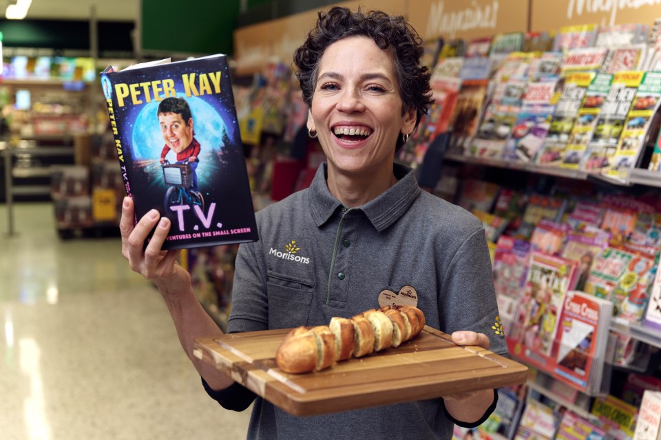 A Morrisons worker posing with the new book and free garlic bread